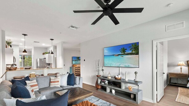 Ein modernes Wohnzimmer mit grauem Sofa, Couchtisch und an der Wand montiertem Fernseher.