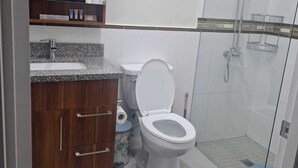 Casa de banho com sanita, lavatório e chuveiro.