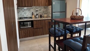 Une cuisine moderne avec des meubles en bois, un pare-feu en marbre et un four encastré. On y trouve également un coin repas avec une table en bois et des chaises rembourrées bleues.