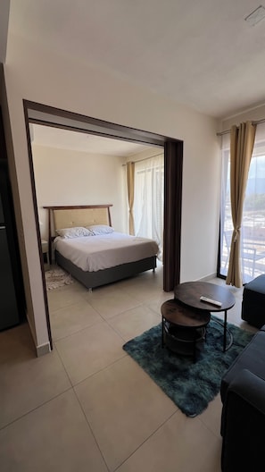 A hotel room with a bed, a small table, a sofa, and a view of the outside. - Vallarta Style: Cozy, Central and Safe Apartment (Puerto Vallarta)