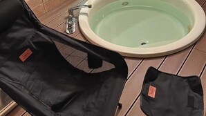 Ein Badezimmer mit einer Badewanne, zwei Stühlen, einem Fenster und einer gefliesten Wand.