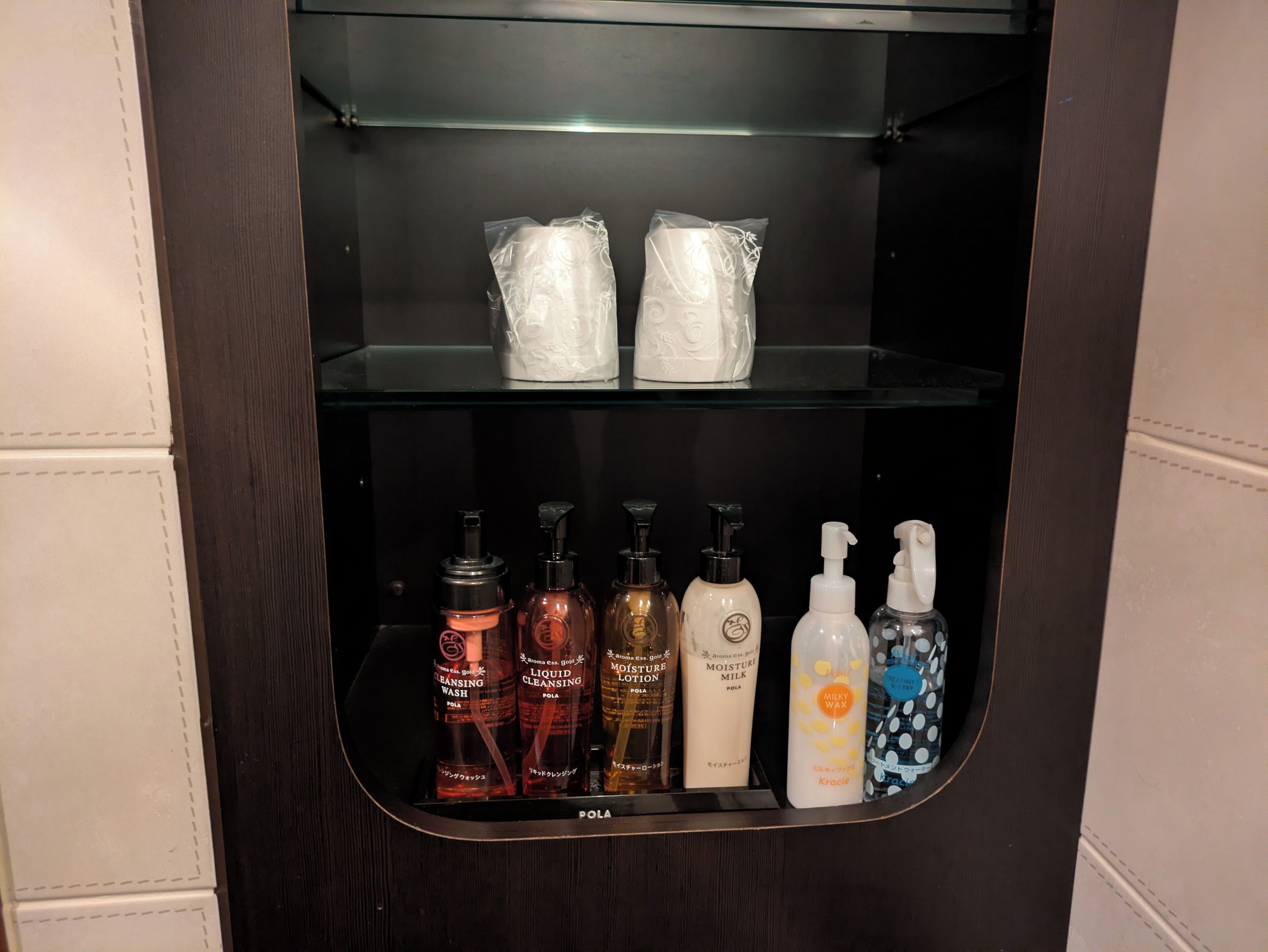 A bathroom cabinet with toiletries including cleansing wash, liquid cleansing, lotion, milk, and wax.