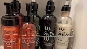 Ein Regal mit verschiedenen Pflegeprodukten wie Reinigungsgel, flüssigem Reinigungsmittel, Shampoo und Conditioner.