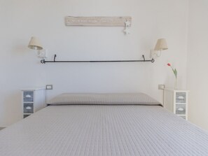 Ein Schlafzimmer mit Bett, Nachttischen, Ablagefläche und einem dekorativen Gegenstand.
