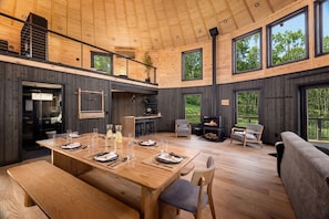 Un interior espacioso de madera con zona de comedor, asientos y chimenea.