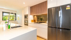 Una cocina moderna con refrigerador de acero inoxidable, horno empotrado y microondas.