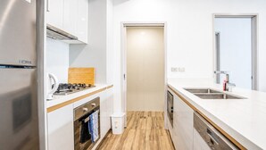 A modern kitchen with white cabinetry, a stainless steel refrigerator, a wooden countertop, and a built-in oven. - Eastgardens 2BR/2BA | 2 Parking + Shops (Eastgardens)