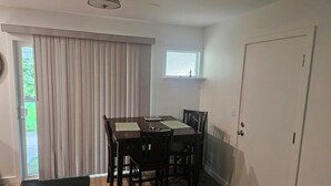 Un comedor con una mesa, sillas, una puerta y un ventanal.
