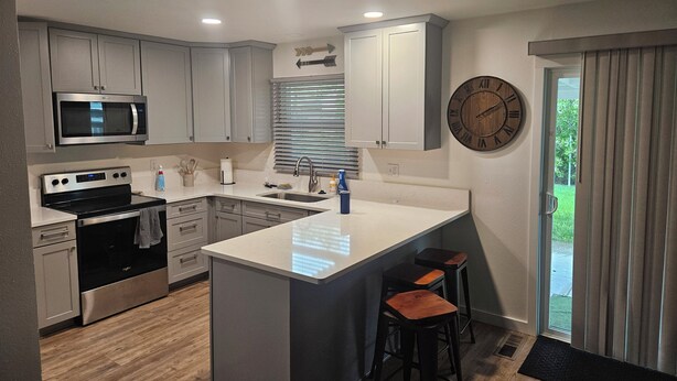 Una cocina moderna con una isla central, electrodomésticos de acero inoxidable y un reloj en la pared.
