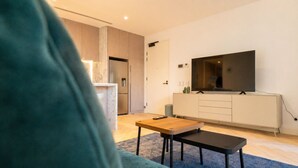 Ett modernt vardagsrum med en platt-TV, ett soffbord i trä och en soffa.