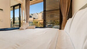 Ett hotellrum med en stor säng, utsikt över omgivningarna och en skjutdörr i glas.