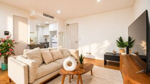 A modern living room with a sofa, coffee table, and TV stand. - Waterloo 2BR/2BA | Pool, Parking, Near Green Sq (Waterloo)