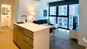 Eine moderne Küche mit Kochinsel, einem Essbereich mit einer Couch und einem großen Fenster mit Blick auf die Stadt.