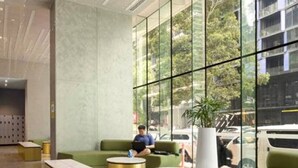 Eine moderne Lobby mit Sitzbereich, einem großen Fenster und einer Person, die einen Laptop benutzt.