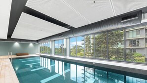 Moderni sisäuimahalli, jossa on suuret ikkunat, laatoitettu lattia ja perforoitu kuvioitu katto.