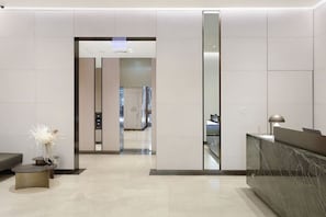 A modern reception area with a marble counter, a small table with a vase, and a hallway leading to an elevator. - 2BR by Circular Quay | The Rocks + Free Parking (The Rocks)
