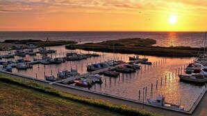 Un port esportiu amb vaixells amarrats, un moll i un capvespre al fons.