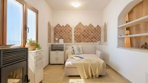 A compact living space with a kitchenette, a sofa, a small cabinet, and a decorative wall with geometric patterns.