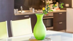 A modern kitchen with a green vase on a table.
