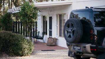 A white building with a paved driveway, a black SUV parked in front, and a wicker basket near the entrance.