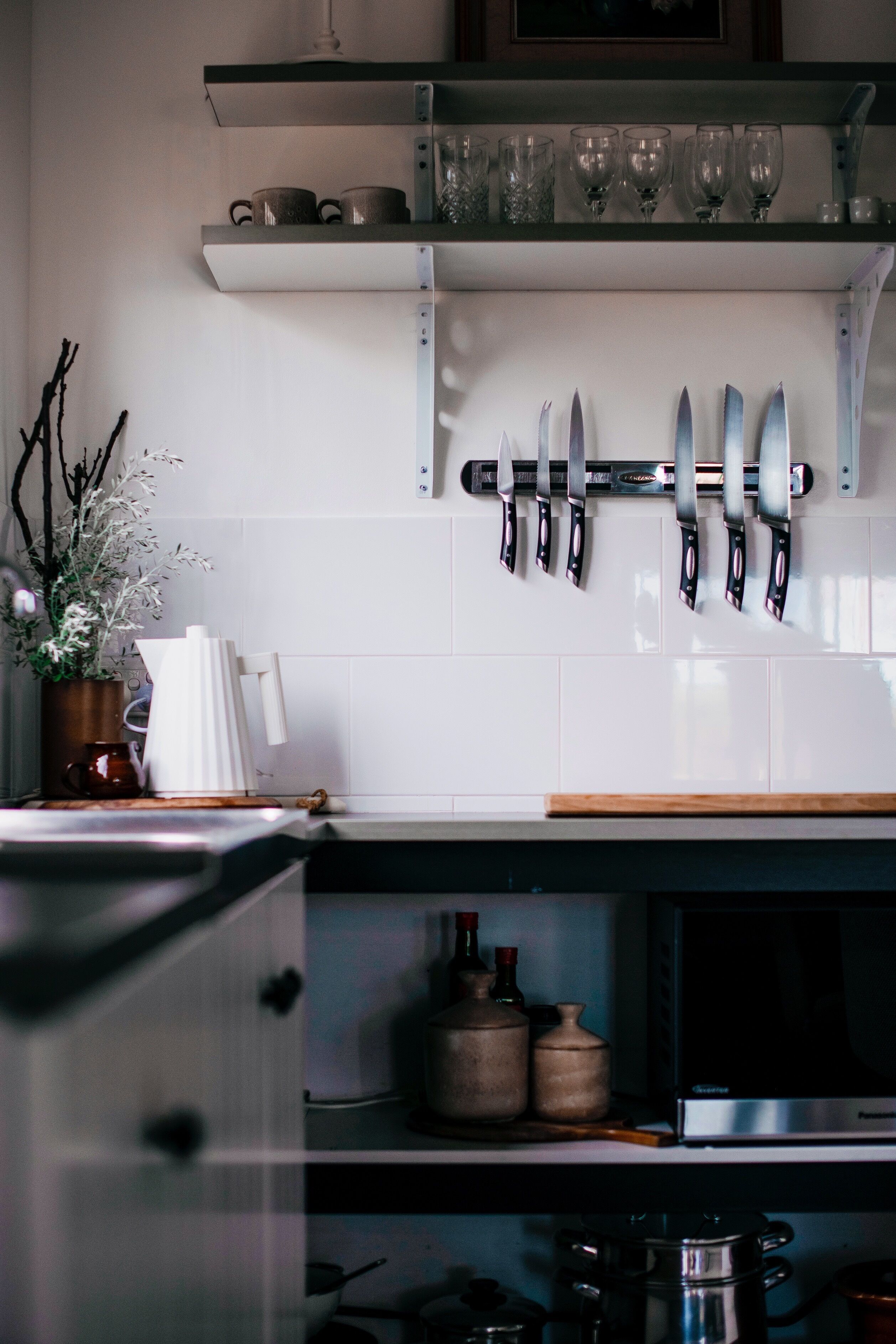 A kitchen with a knife rack, a potted plant, and various kitchen items on the counter.