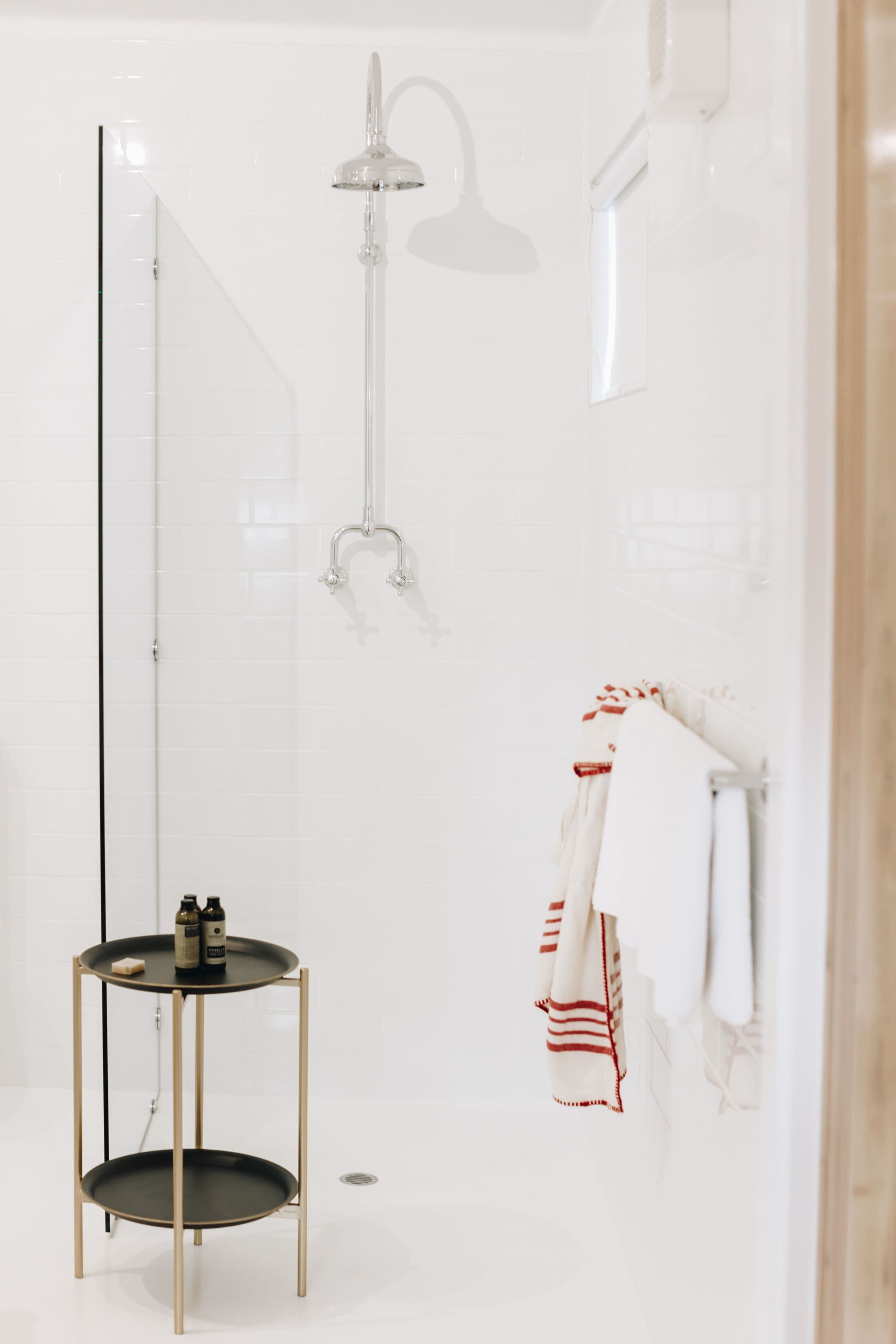 Une salle de bain moderne avec une douche à parois de verre, un porte-serviettes avec une serviette, et une petite table avec des articles de toilette.