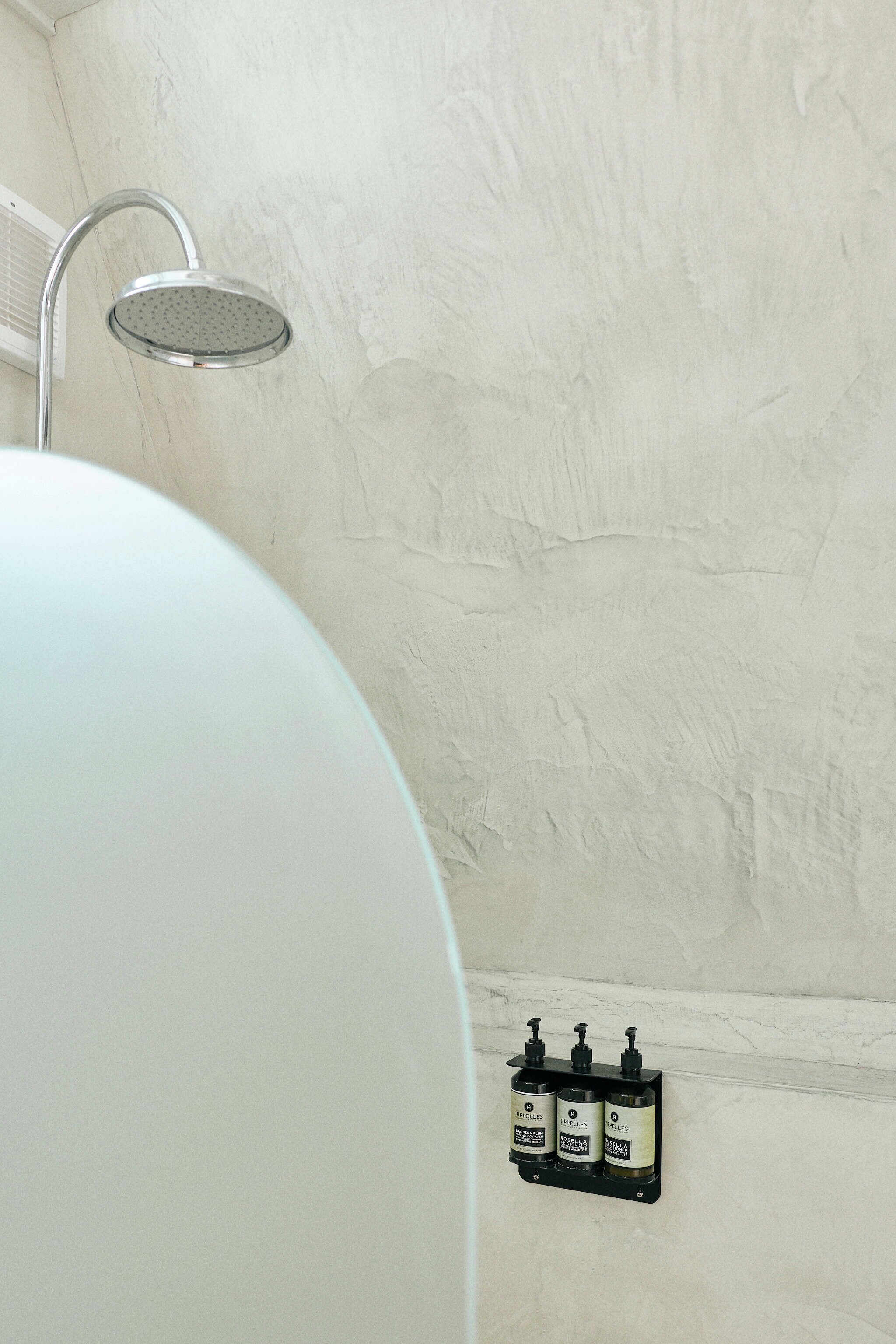 A bathroom with a shower, a sink, and a wall-mounted soap dispenser.