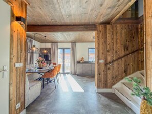 Ein modernes Interieur mit Holzboden, einem Essbereich mit Tisch und Stühlen sowie einer durchgehenden Tür erkennbaren Küche.