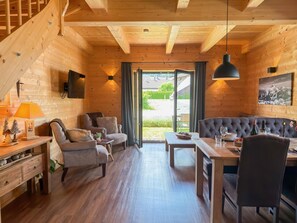 A log cabin interior with a sofa, chairs, a dining table, and a staircase. - Chalet with garden located near Nassfeld area (Rattendorf)