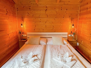 Ein holzgetäfeltes Zimmer im Chalet-Stil mit einem Doppelbett, zwei Nachttischen und Wandlampen.