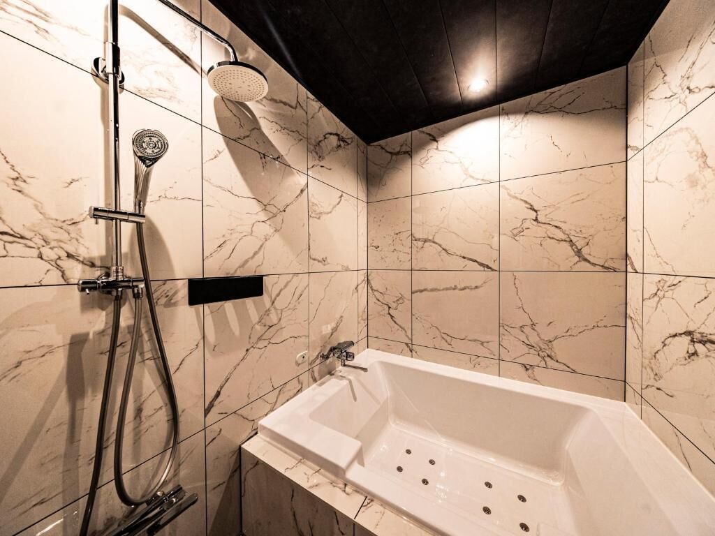 Un baño con bañera, ducha y azulejos de mármol.