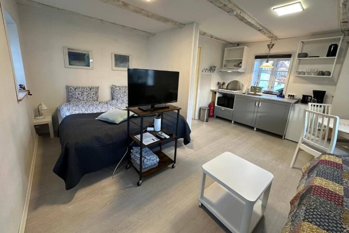Ein Schlafzimmer mit Bett, Fernseher, Nachttisch und einem kleinen weißen Tisch.