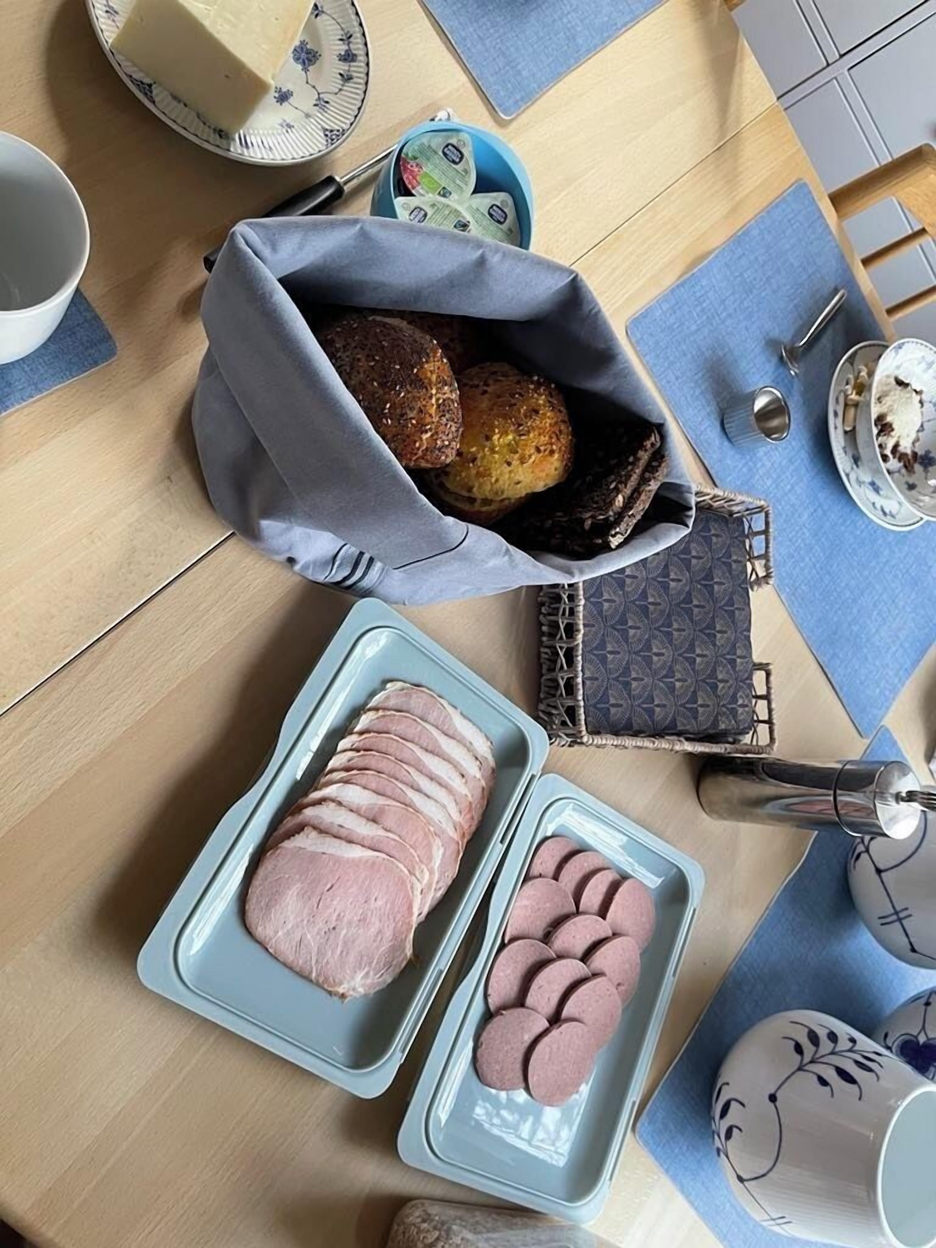 Et bord med et brød, en dåse kiks, en bakke med skåret kød og en bakke med runde skiver af kød.