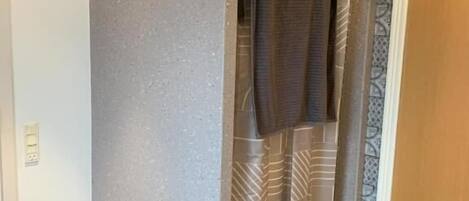 Ein Badezimmer mit Duschvorhang, einer Tür und einer Wand mit Muster.