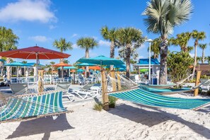Ein Strandbereich mit Hängematten, Sonnenschirmen und Liegestühlen.