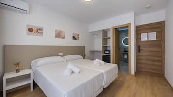 A modern hotel room with a large bed, bedside tables, a wardrobe, and a bathroom visible through an open door.