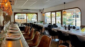 Un restaurante con una barra larga, sillas de cuero y mesas dispuestas para comer.