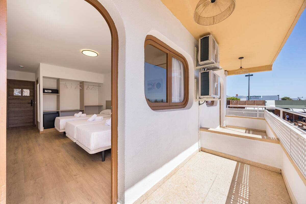 A balcony with a view, a room with two beds, and a small window.