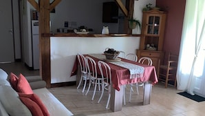 En stue med sofa, spisebord med stole, et køkken og en loftventilator.