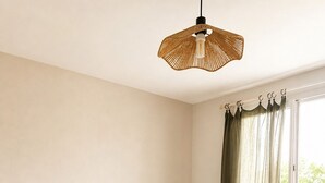 Et soveværelse med seng, sengebord, lampe og et vindue med gardiner.