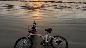 Una bicicleta en la playa con un atardecer de fondo.