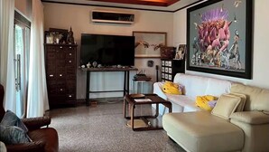 Una sala de estar con un sofá, una mesa de centro, un televisor y un ventilador de techo.