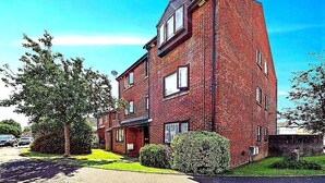 Ein rotes Mehrfamilienhaus mit Flachdach, zahlreichen Fenstern und einer sichtbaren Satellitenschüssel.