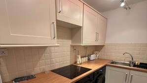 Eine moderne Küche mit weißen Schränken, einer Holz Arbeitsplatte, einem eingebauten Ofen, einem Geschirrspüler und einem Spülbecken.