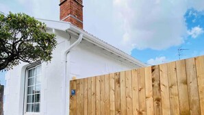 Un edificio blanco con valla de madera, una ventana y una chimenea de ladrillo.