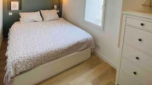 Un dormitorio con cama, lámparas de noche, cómoda y ventana.