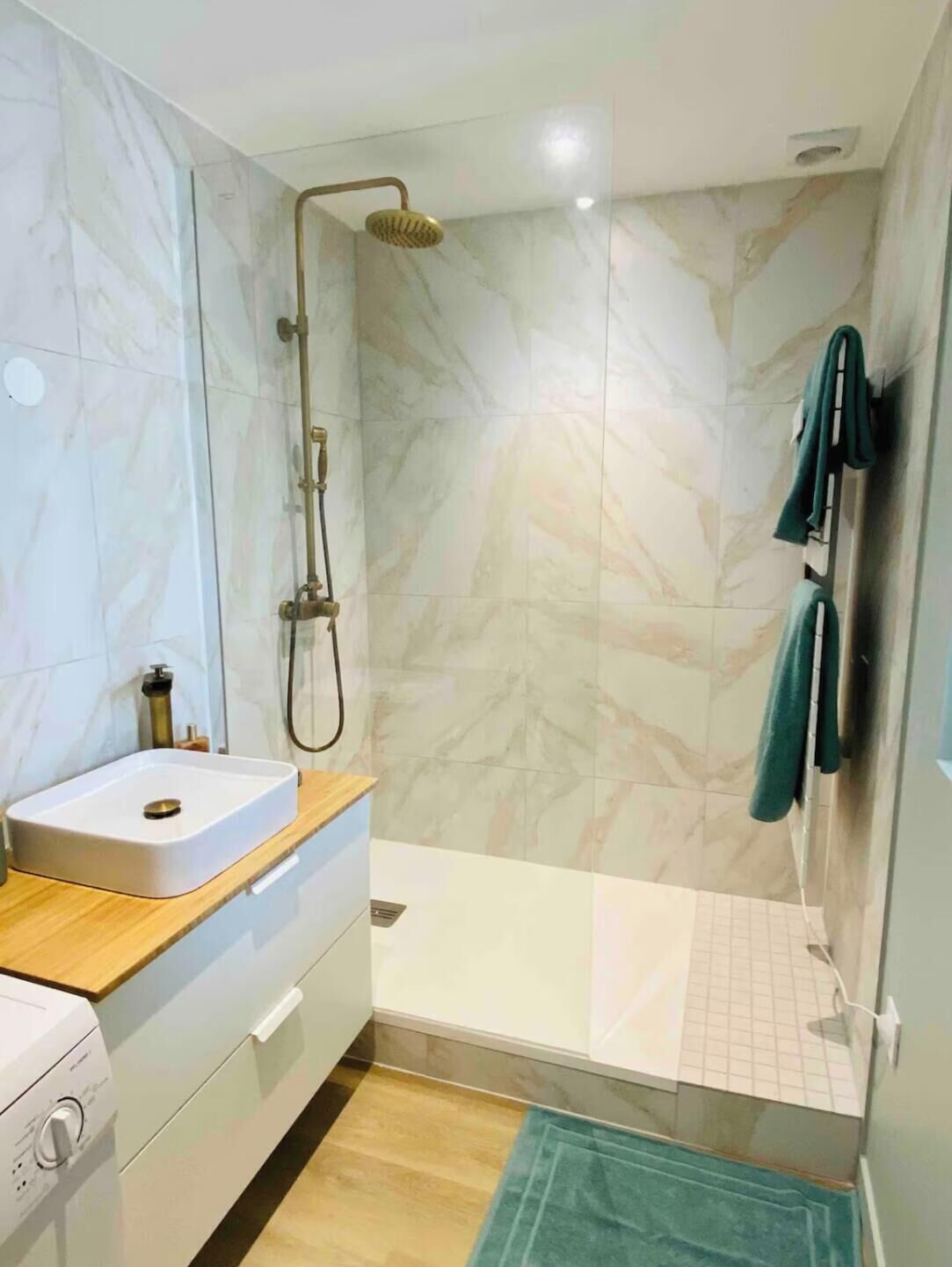 Een badkamer met een douche, een wastafel en een handdoekhouder.