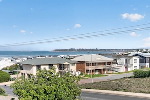 A coastal residential area with modern houses, a clear view of the ocean, and a street with power lines overhead. - The Palms Sea Breeze Middleton (Middleton)