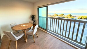 A balcony with a view of the sea, a dining table with chairs, and a potted plant. - Seaside Escape at New Brighton with Carpark (Christchurch)