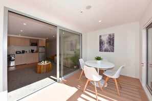 Un intérieur moderne comprenant un coin repas, une cuisine et des portes-fenêtres coulissantes donnant sur un balcon.